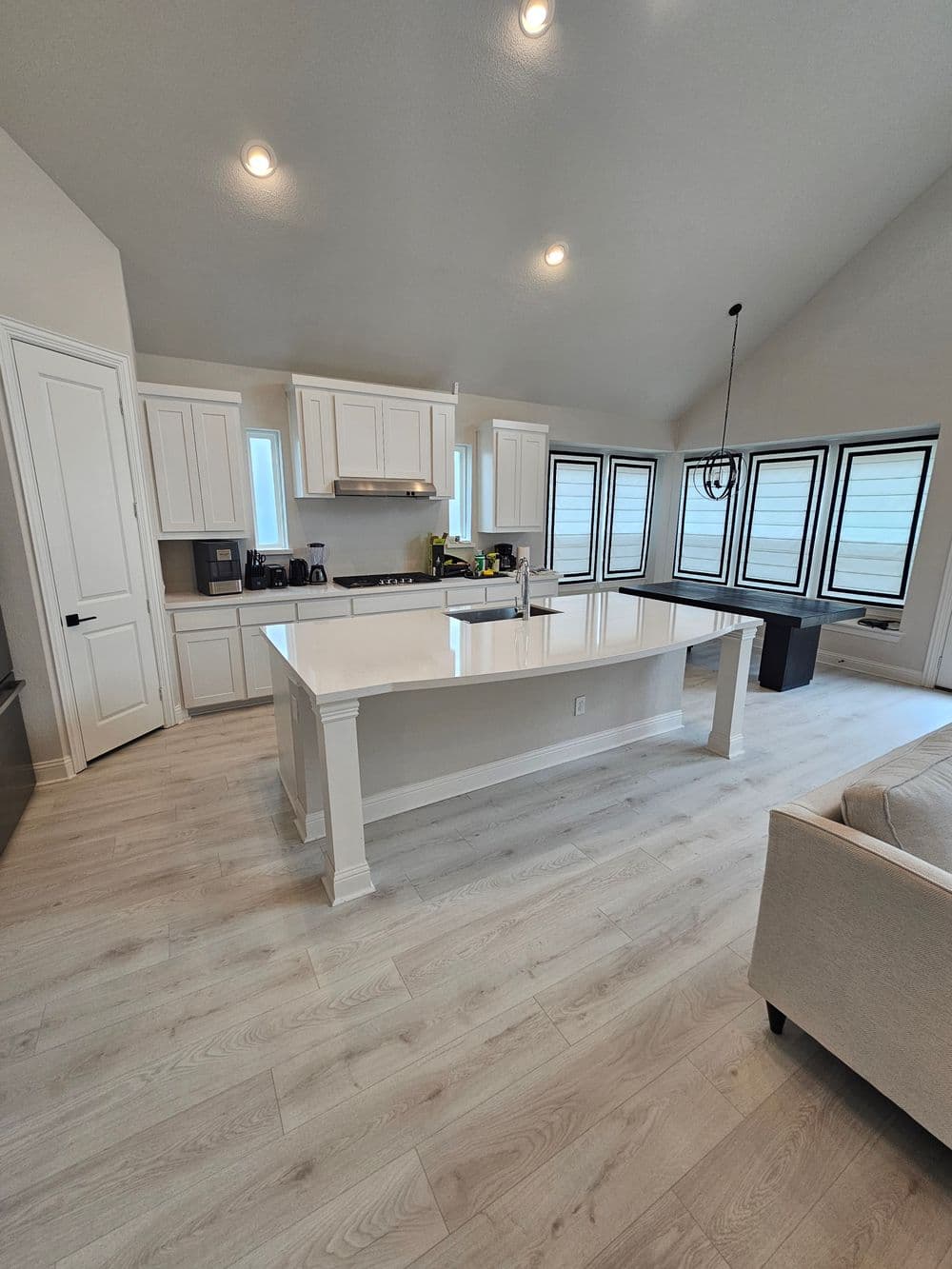 Modern kitchen with white cabinetry, large island, and skylights in open layout.