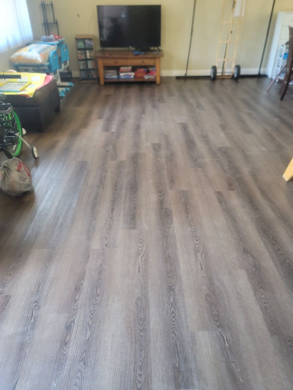 Living room with dark wood flooring, TV, and furniture, creating a cozy atmosphere.