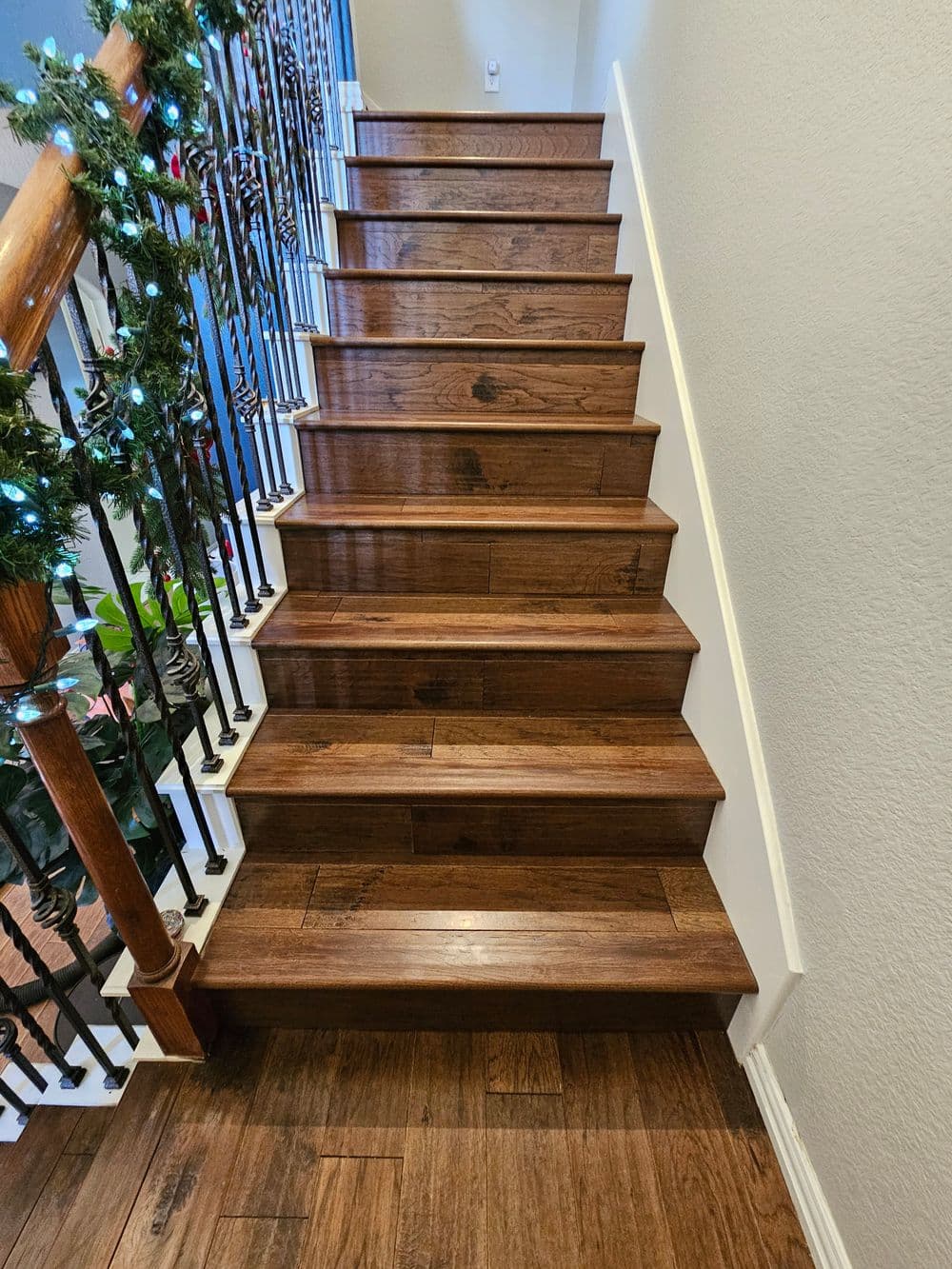 Beautiful wooden staircase with decorative railing and holiday greenery. Bright and inviting interior.