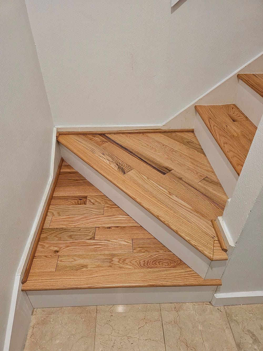 Modern wooden staircase with angled steps and polished light oak flooring.