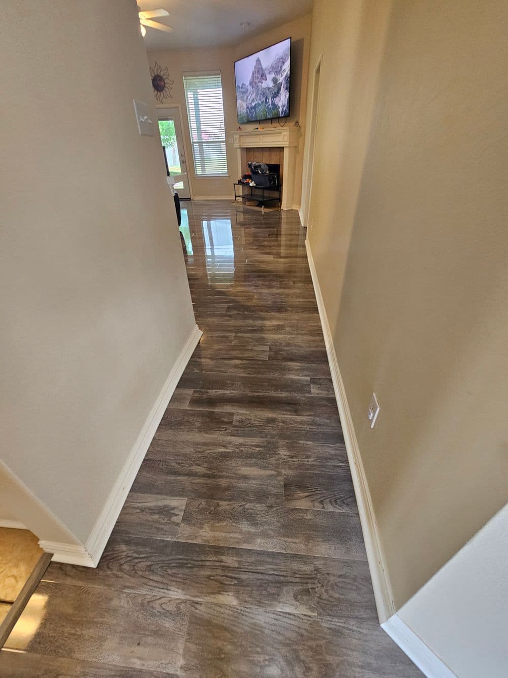 Spacious hallway with wooden floors, leading to a living area and fireplace.