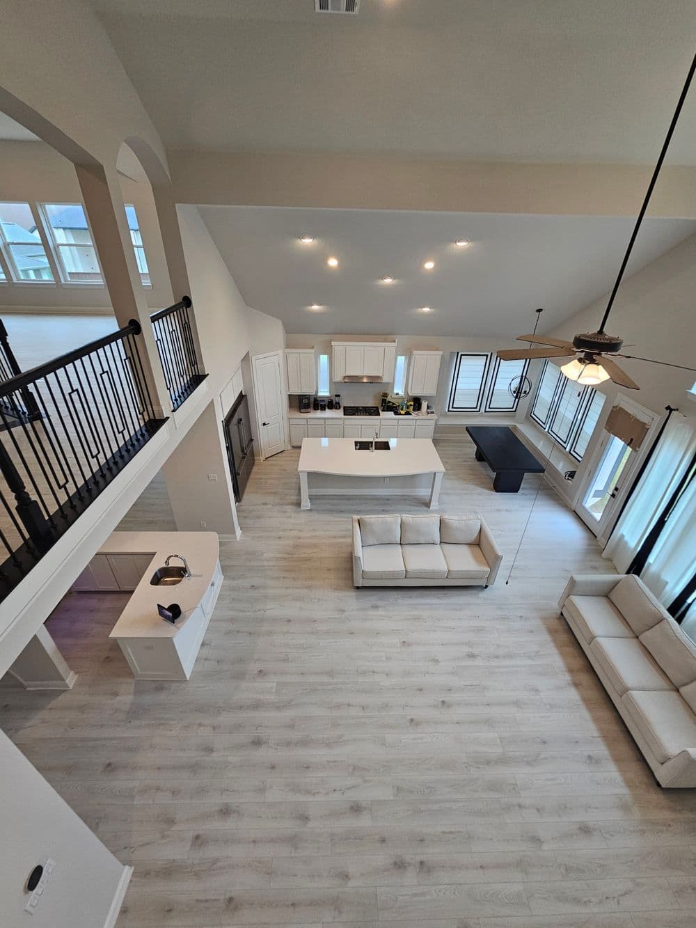 Spacious modern living room and kitchen with white furniture and large windows.