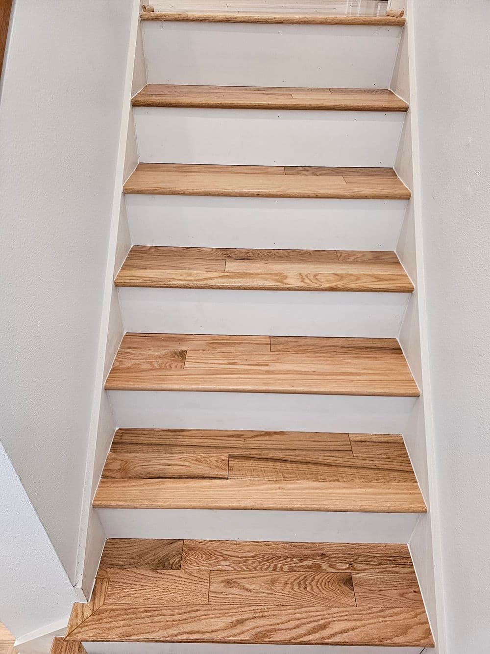 Interior wooden staircase with light oak steps and white risers leading upwards.
