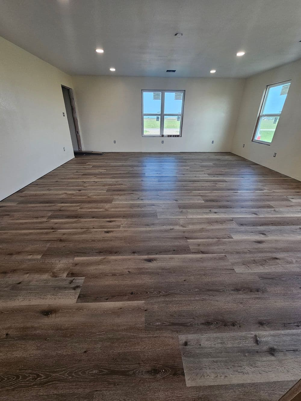 Spacious room with new hardwood flooring and large windows for natural light.