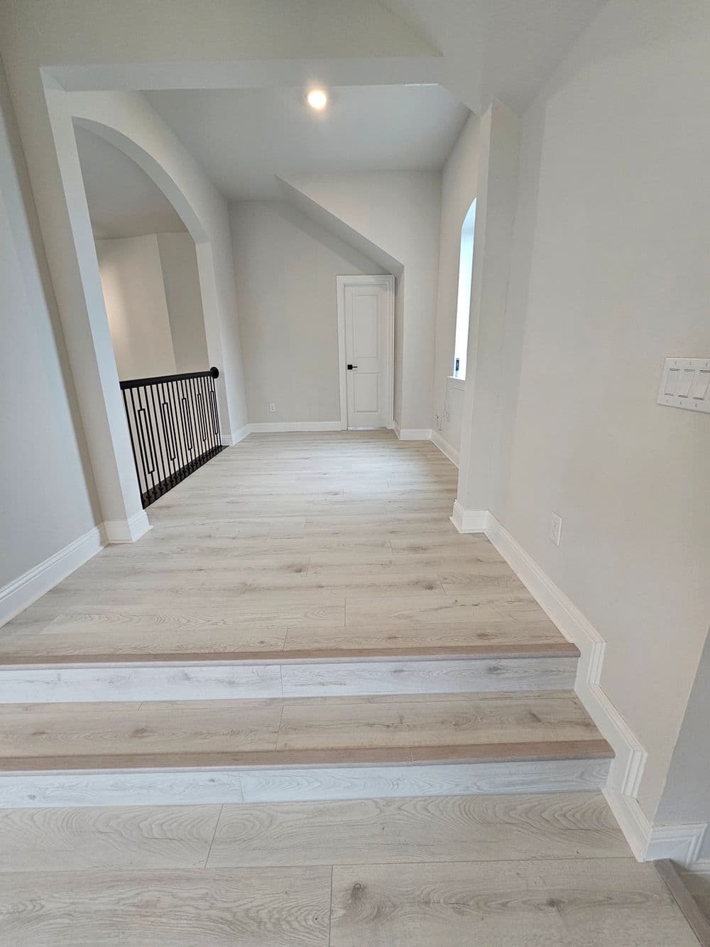 Spacious hallway with light wood flooring and elegant railing in modern interior design.
