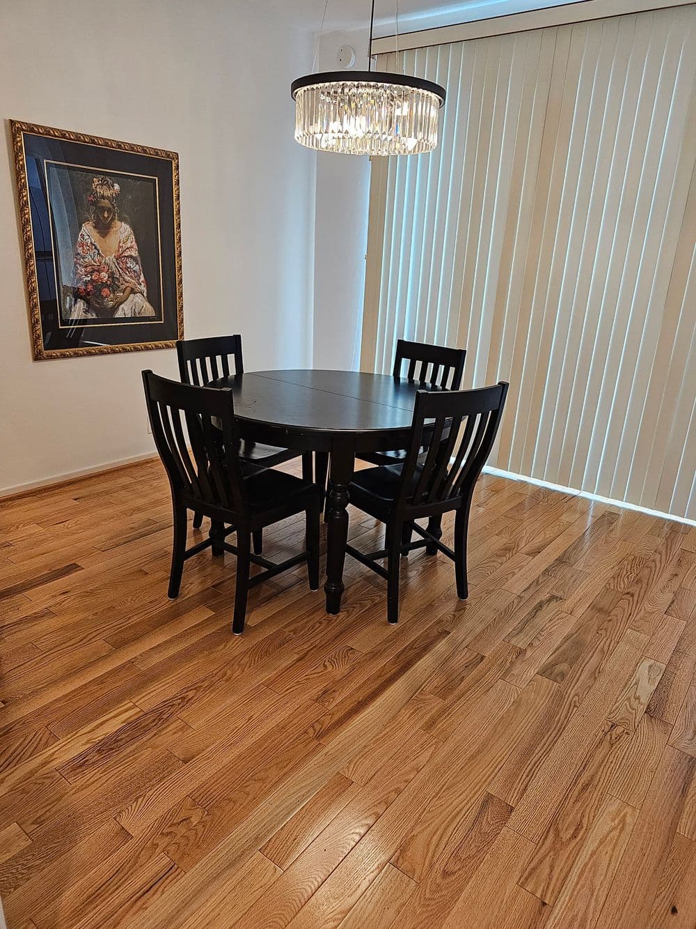Modern dining room with a round black table, four chairs, and a stylish chandelier.