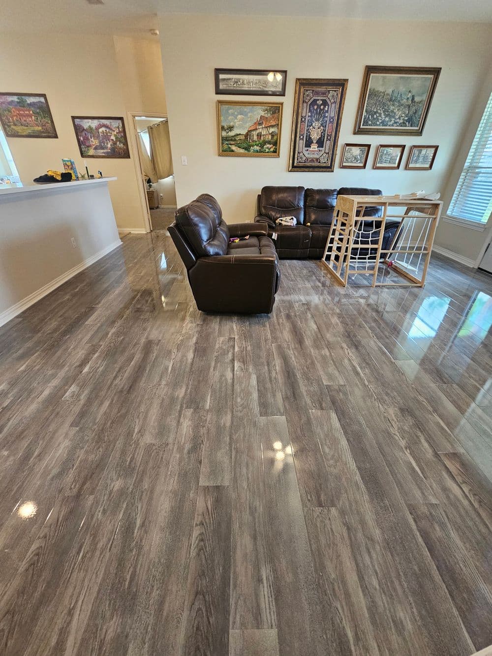 Modern living room with gray wooden floors, leather seating, and decorative wall art.