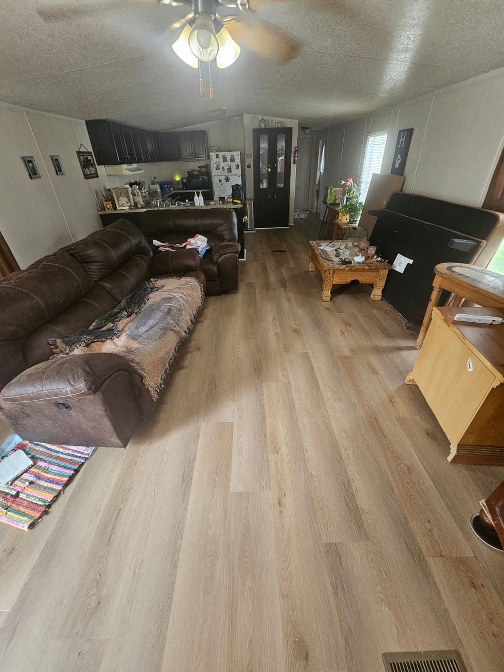 Cozy living room with brown sofas, wood flooring, and bright lighting.