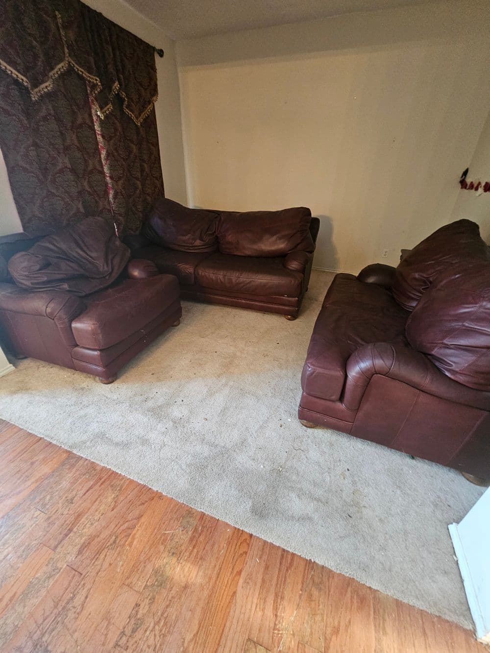 Living room with brown leather couches and an area rug on wooden flooring.