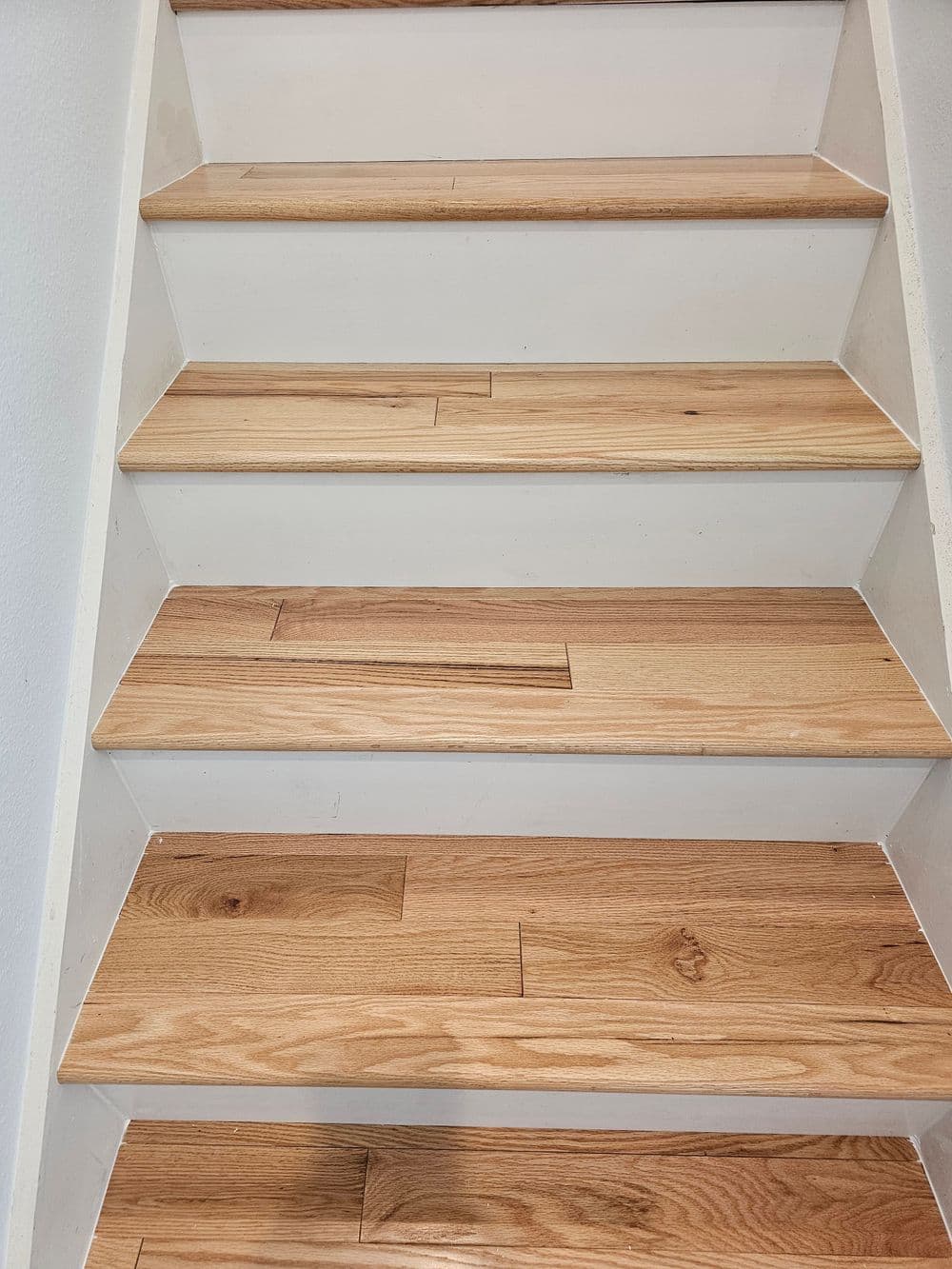 Stunning wooden staircase with polished oak steps and white risers, showcasing modern design.