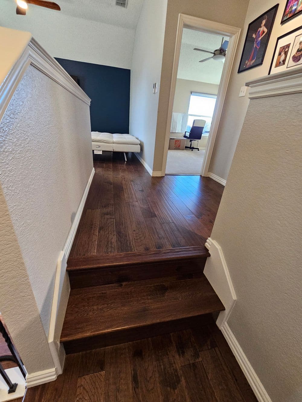 Staircase leading to a hallway with wooden floors and a dark accent wall.