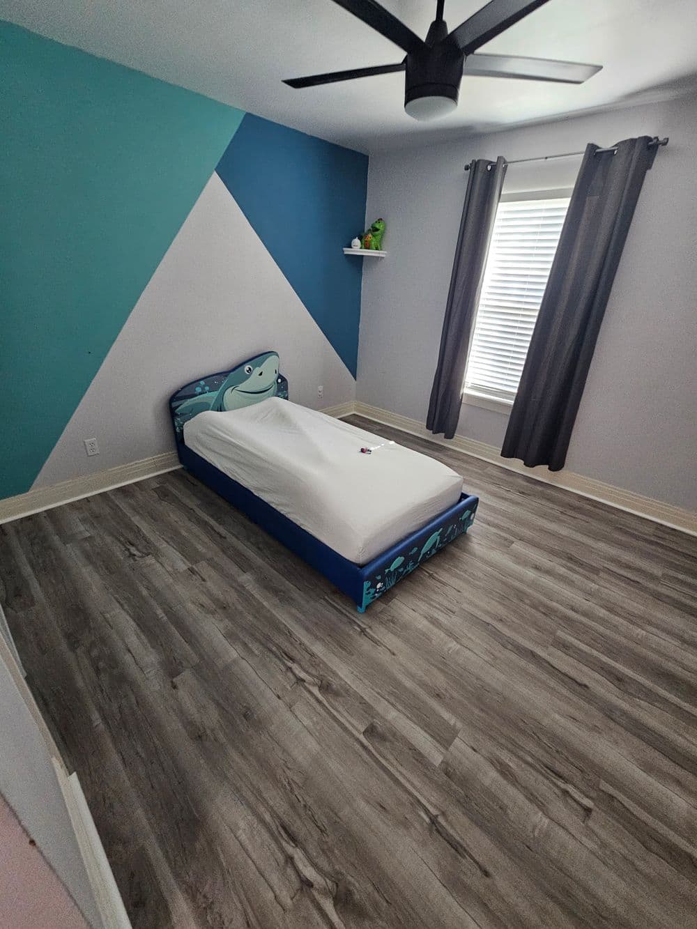 Colorful children's bedroom with a single bed and playful wall design, featuring large windows.