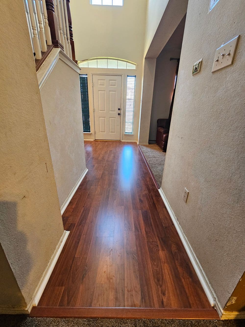 Welcoming hallway with hardwood floor, leading to front door and natural light.