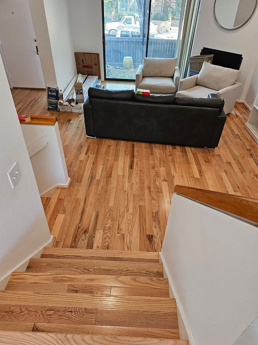 View of a modern living room with hardwood floors, staircase, and comfortable seating.