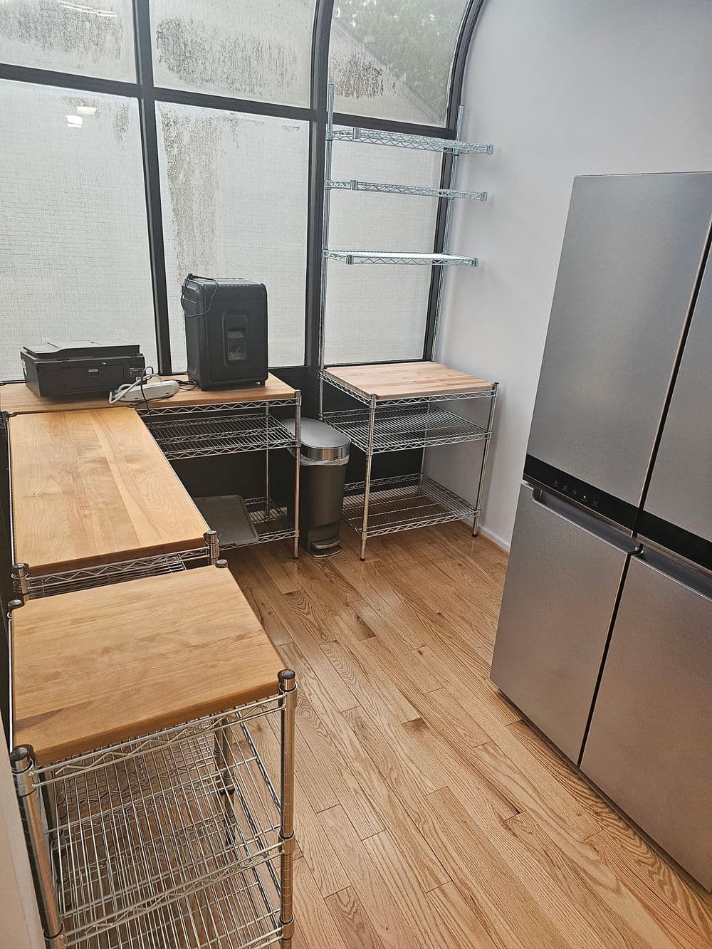 Modern kitchen featuring stainless steel refrigerator, wooden countertops, and open shelving.