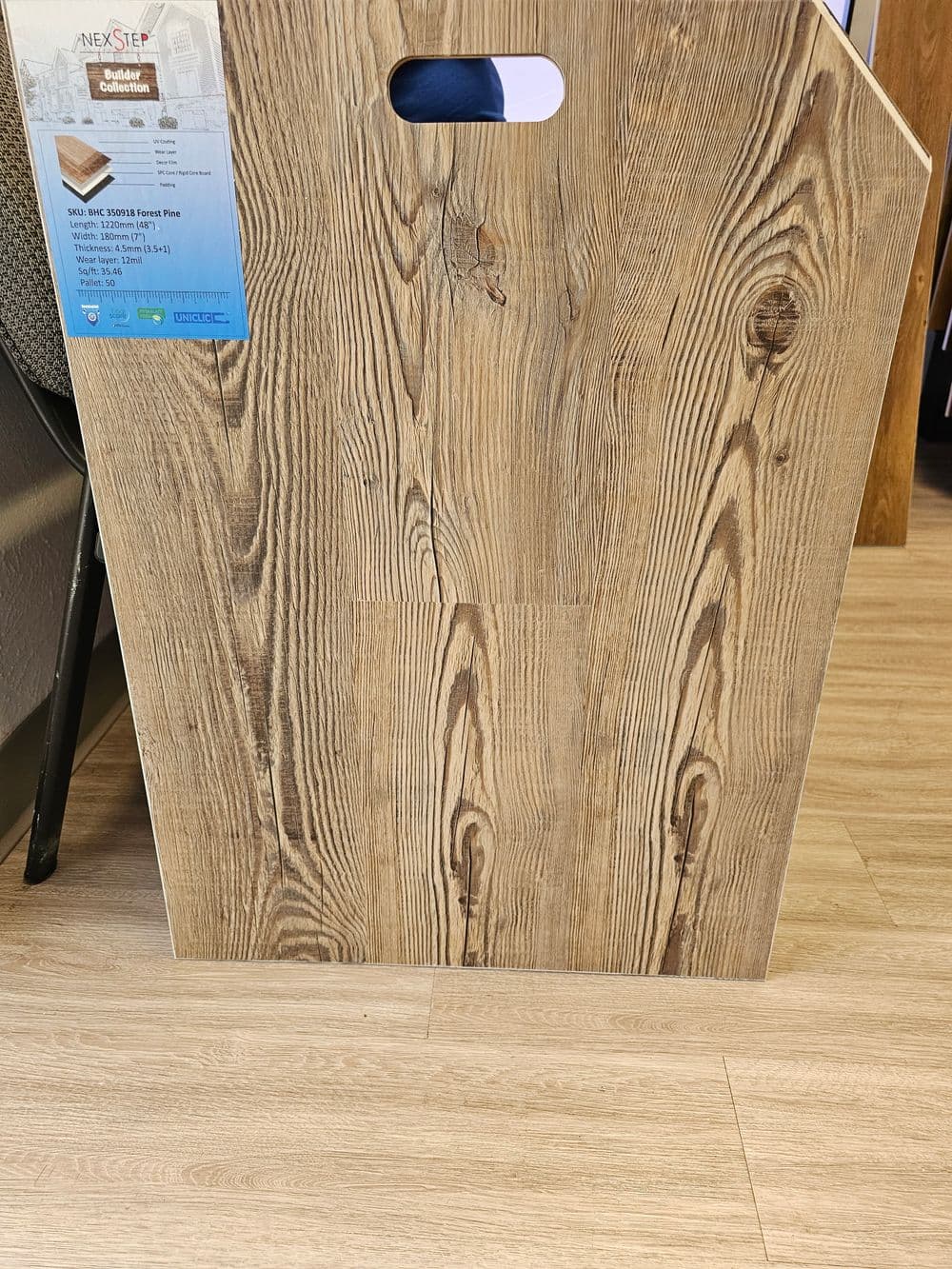 Natural wood grain laminate flooring sample with carrying handle, showcasing texture and color.