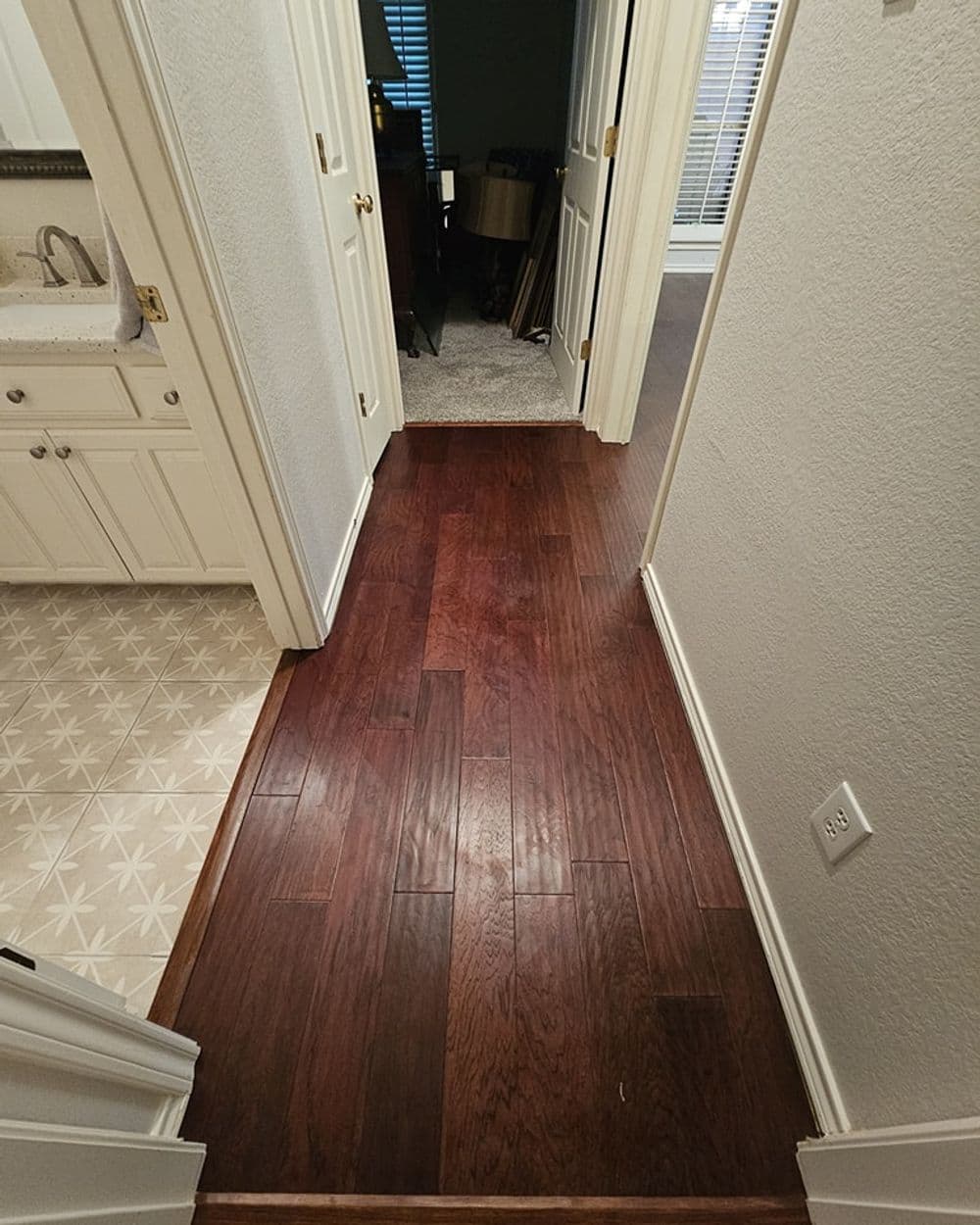 Wooden hallway flooring transitioning from tiles to hardwood in a modern home.