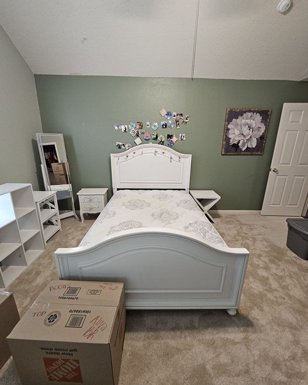 White bedroom furniture with a bed, nightstand, mirror, and decor on green walls.