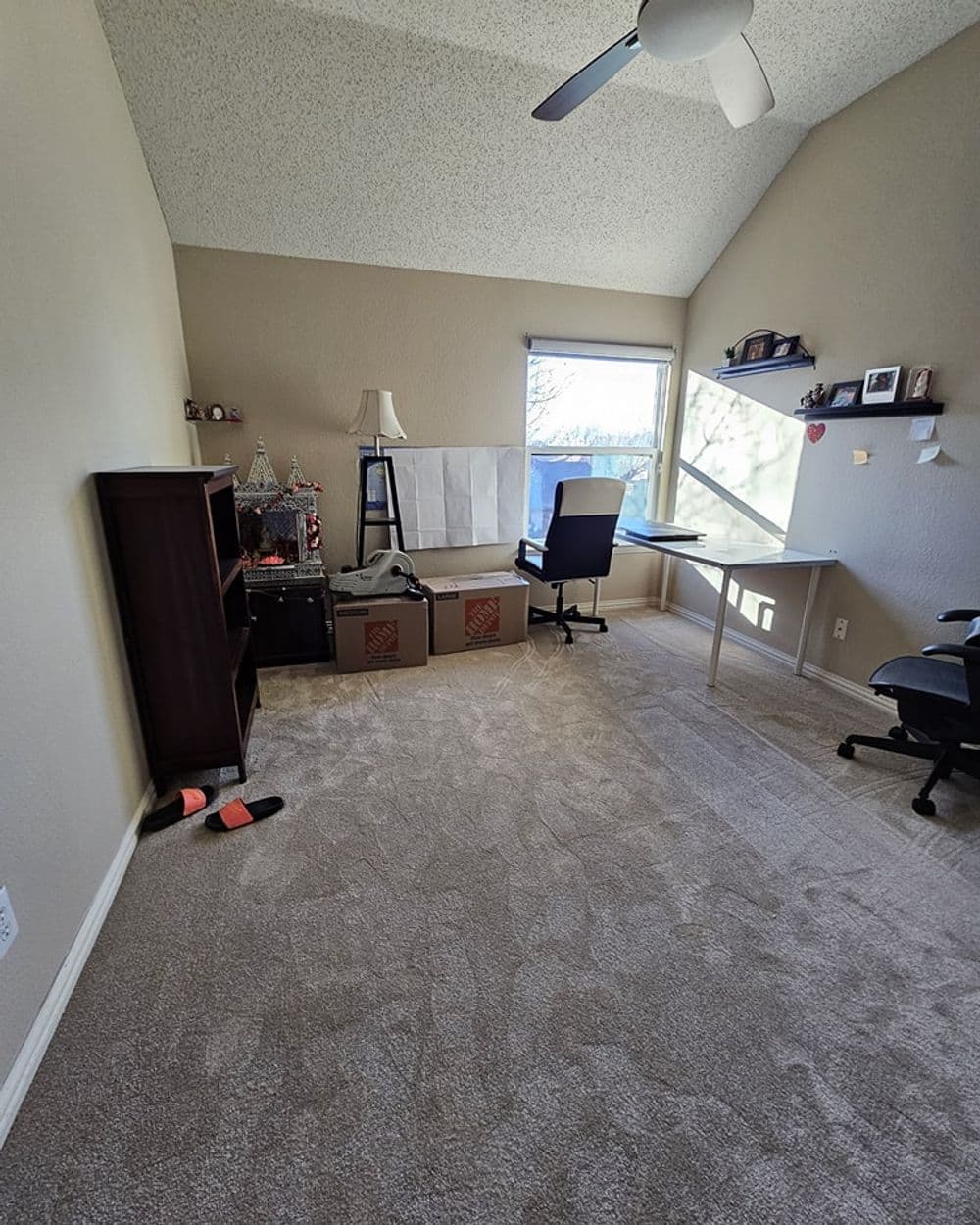 Spacious home office with desk, chair, bookshelves, and natural light from window.