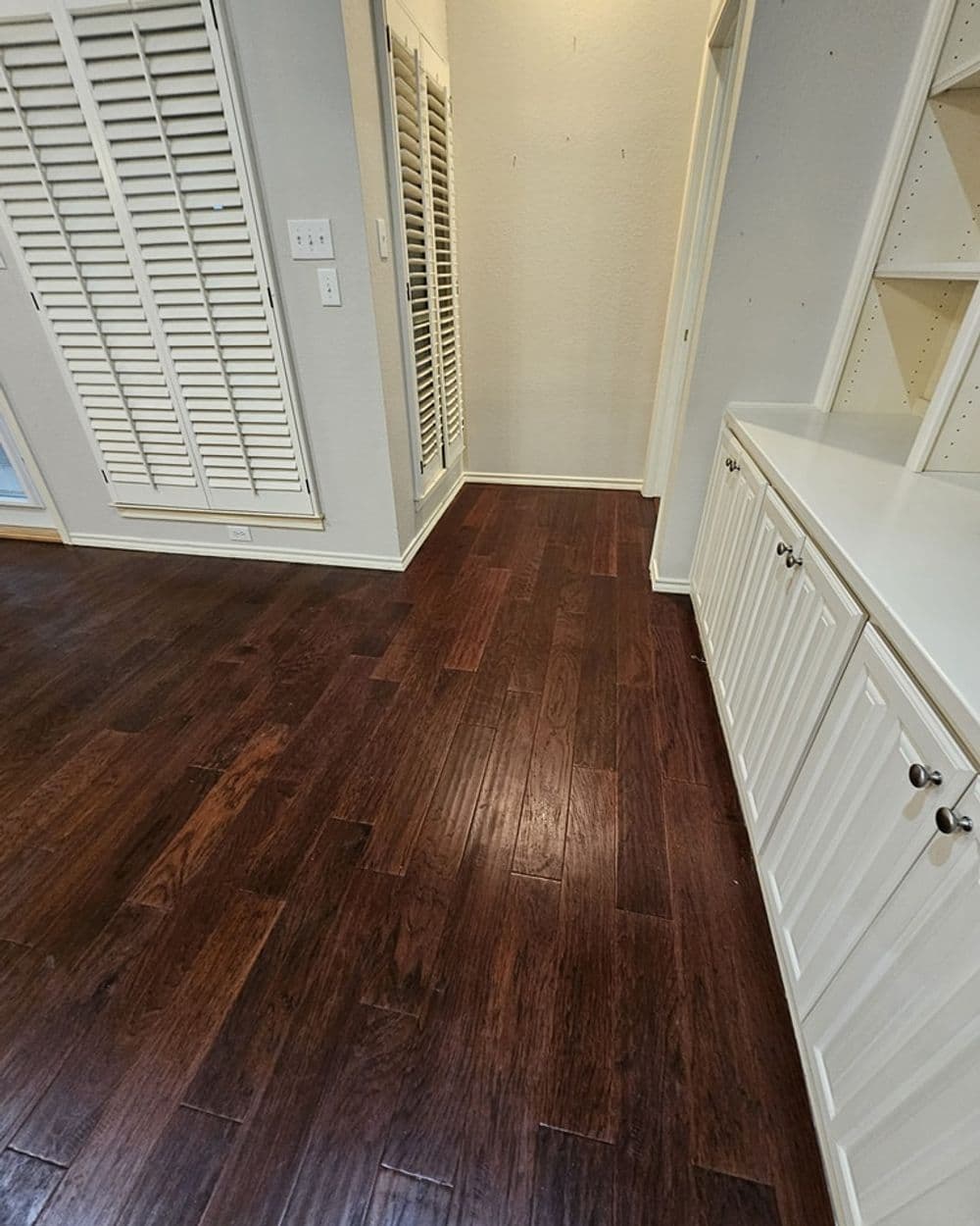 Spacious hallway with hardwood flooring, built-in cabinets, and mirrored closet doors.