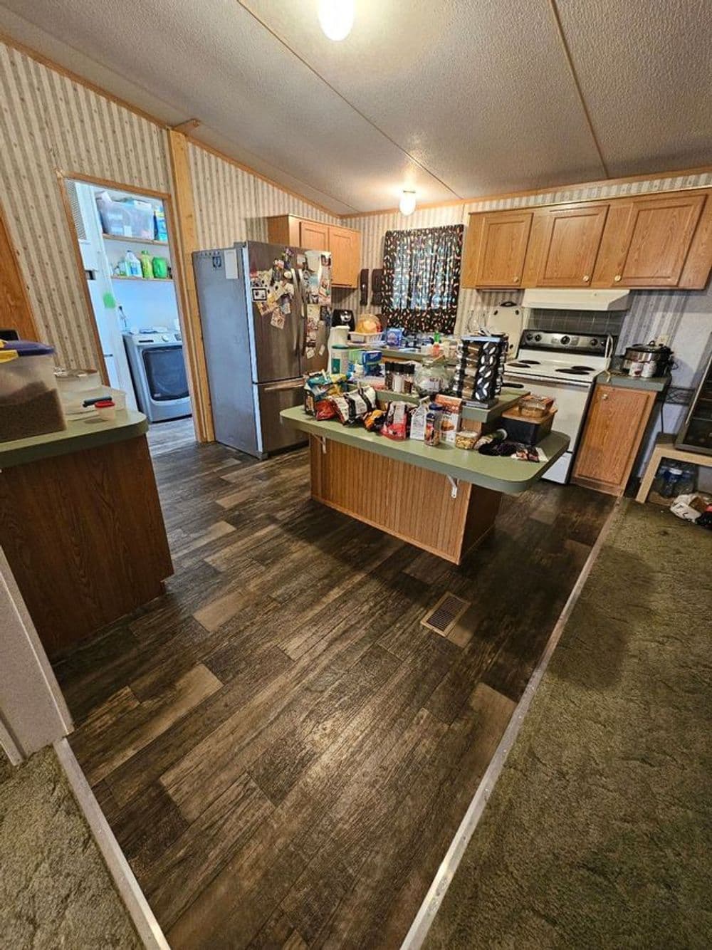 Spacious kitchen with wooden cabinets, pantry items on the island, and a laundry room doorway.